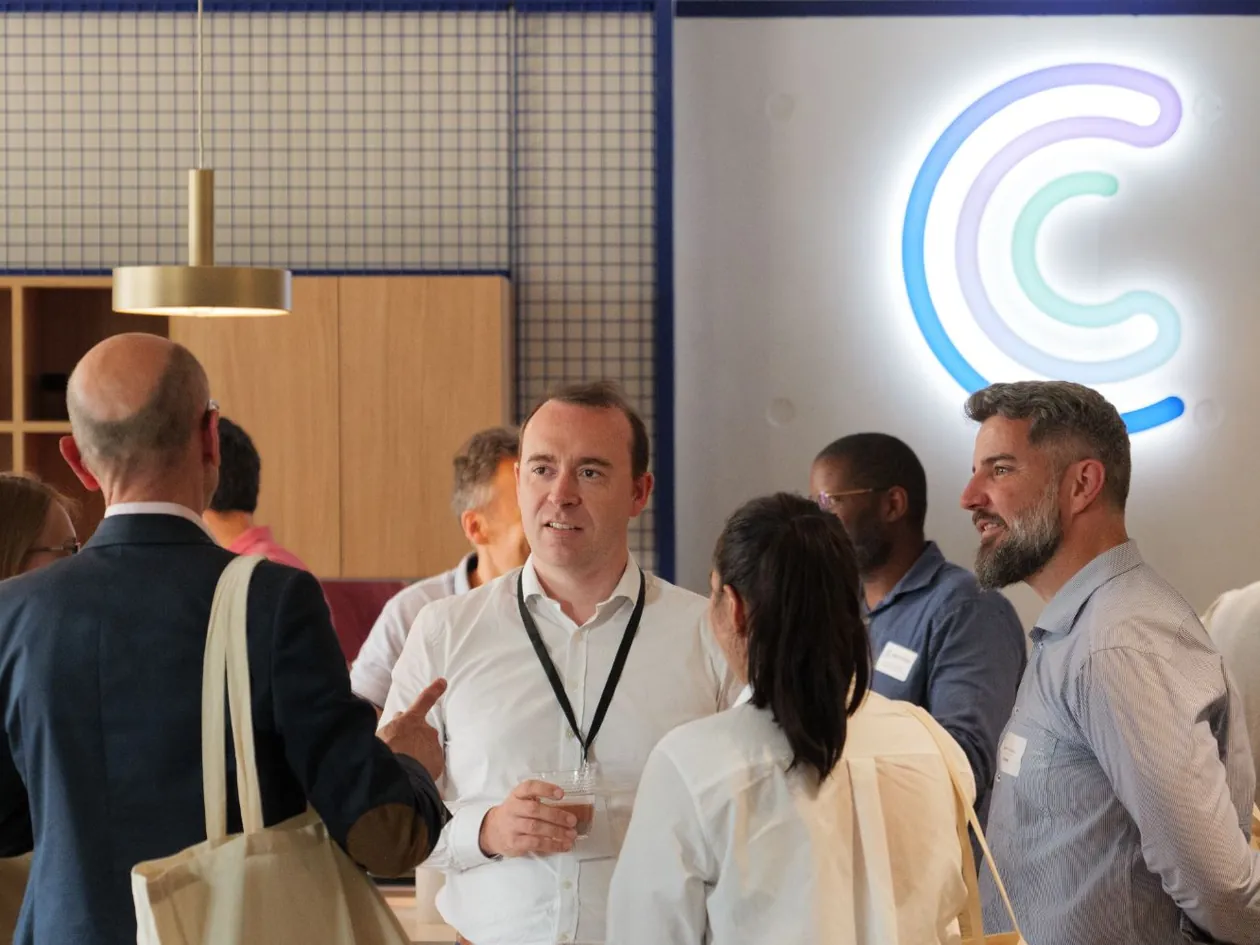 Centreon's CEO talking with guests at an event in Centreon's offices, beneath the illuminated Centreon logo